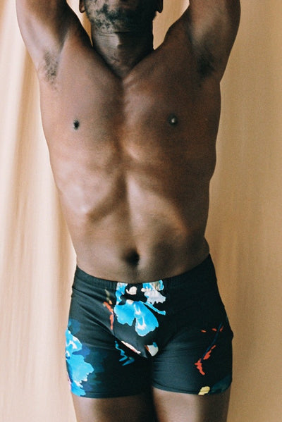 close up of a men in a yoga pose with the black flower printed yoga wear. super comfortable yoga short for men 